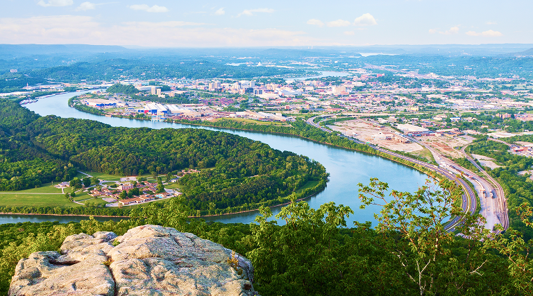 Aerial view of the Tennessee River curving around downtown Chattanooga lined by lush greenery
